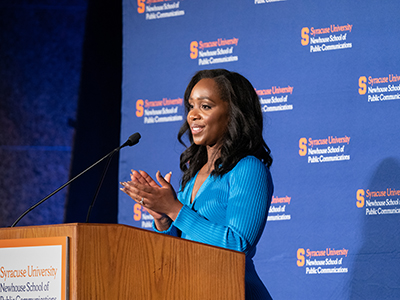 Woman standing at podium speaking.