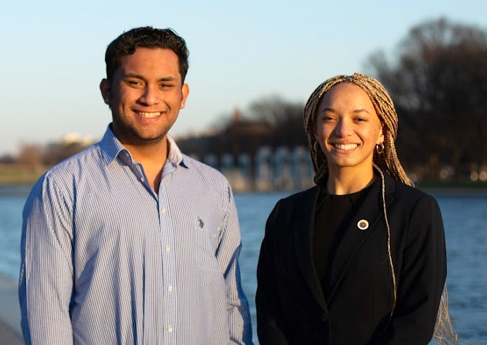 A man and a woman smile while posing for a photo outside.